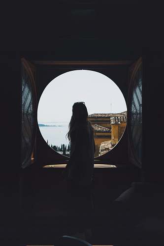 woman woman standing in front of round window silhouette